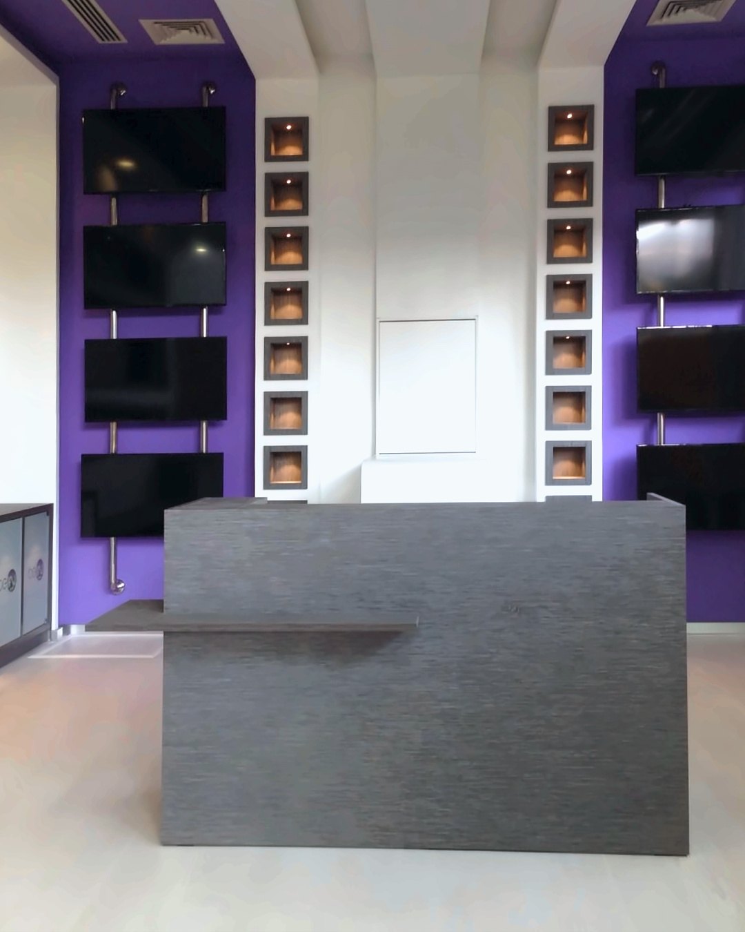 Skranke i grå træstruktur foran tv væg på lilla baggrund i beIN SPORTS butikken i Doha