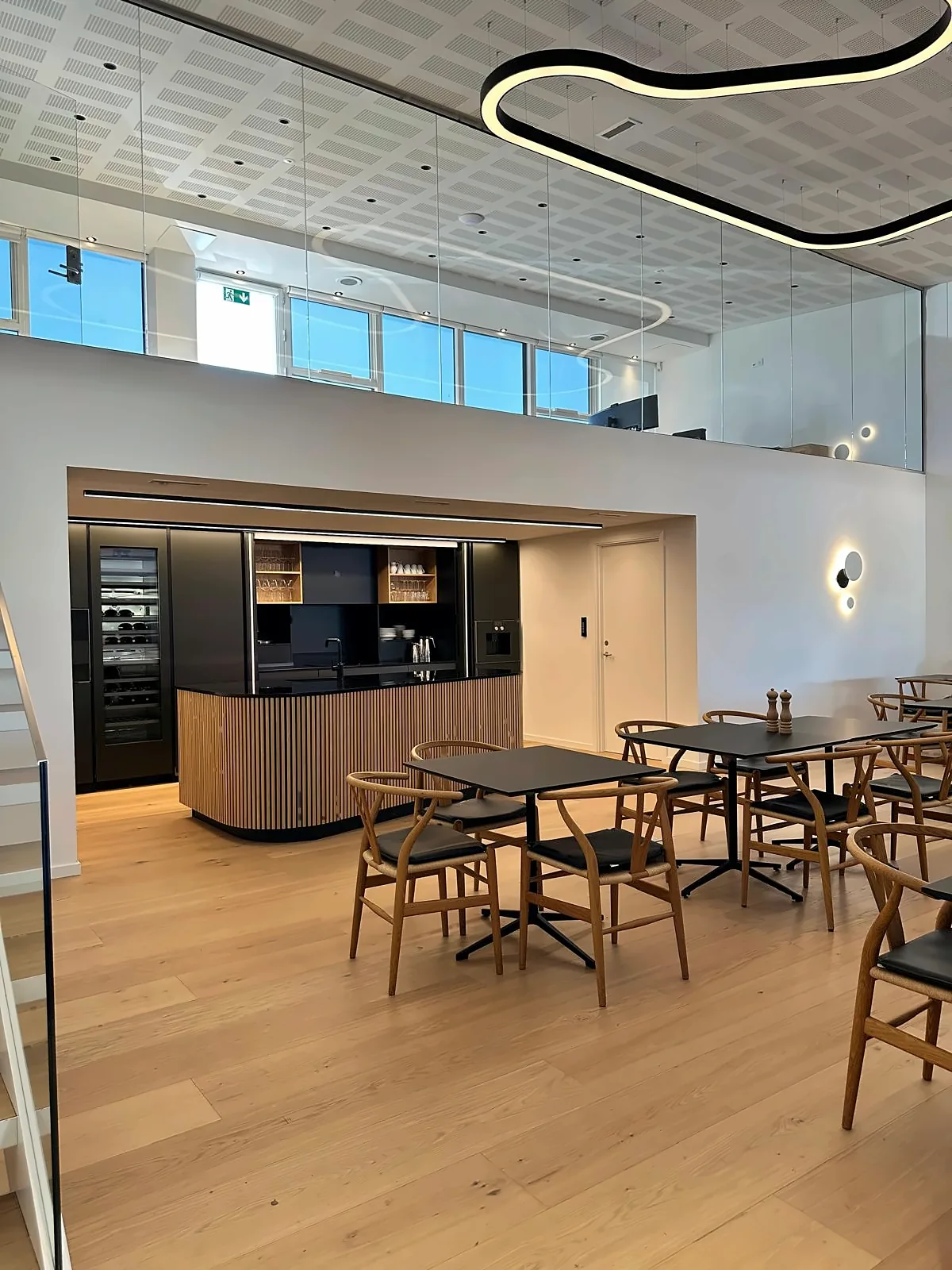 Kantine med spisebord og Wishbone stoler ved glassvegg hos Andersen Biler i Gladsaxe